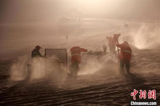 圖為敦煌市鳴沙山月牙泉景區(qū)“駱駝保姆”清理駱駝糞便?！垥粤?攝