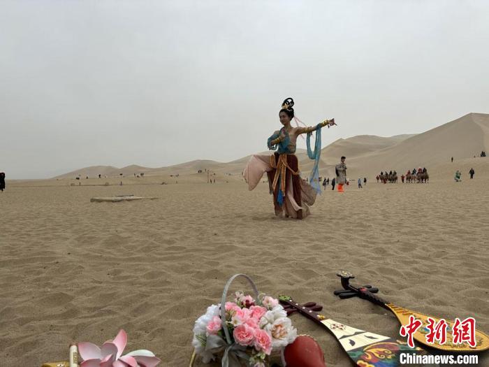 圖為2023年4月底，敦煌大漠“逐舞者”奧楠在鳴沙山月牙泉景區(qū)視頻直播敦煌舞?！●T志軍 攝
